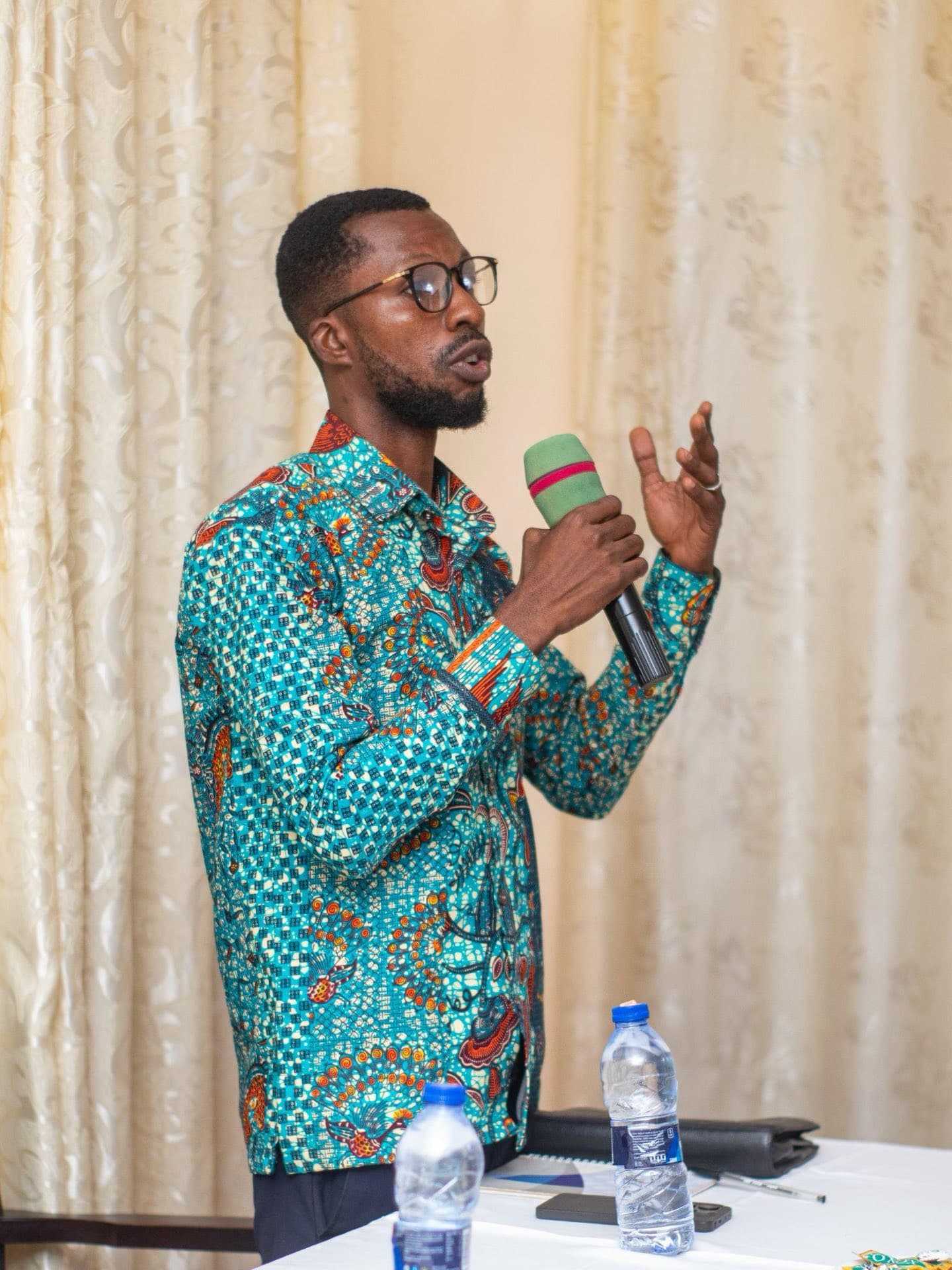 A young AYWF delegate speaking into a microphone at a water forum session in Ghana