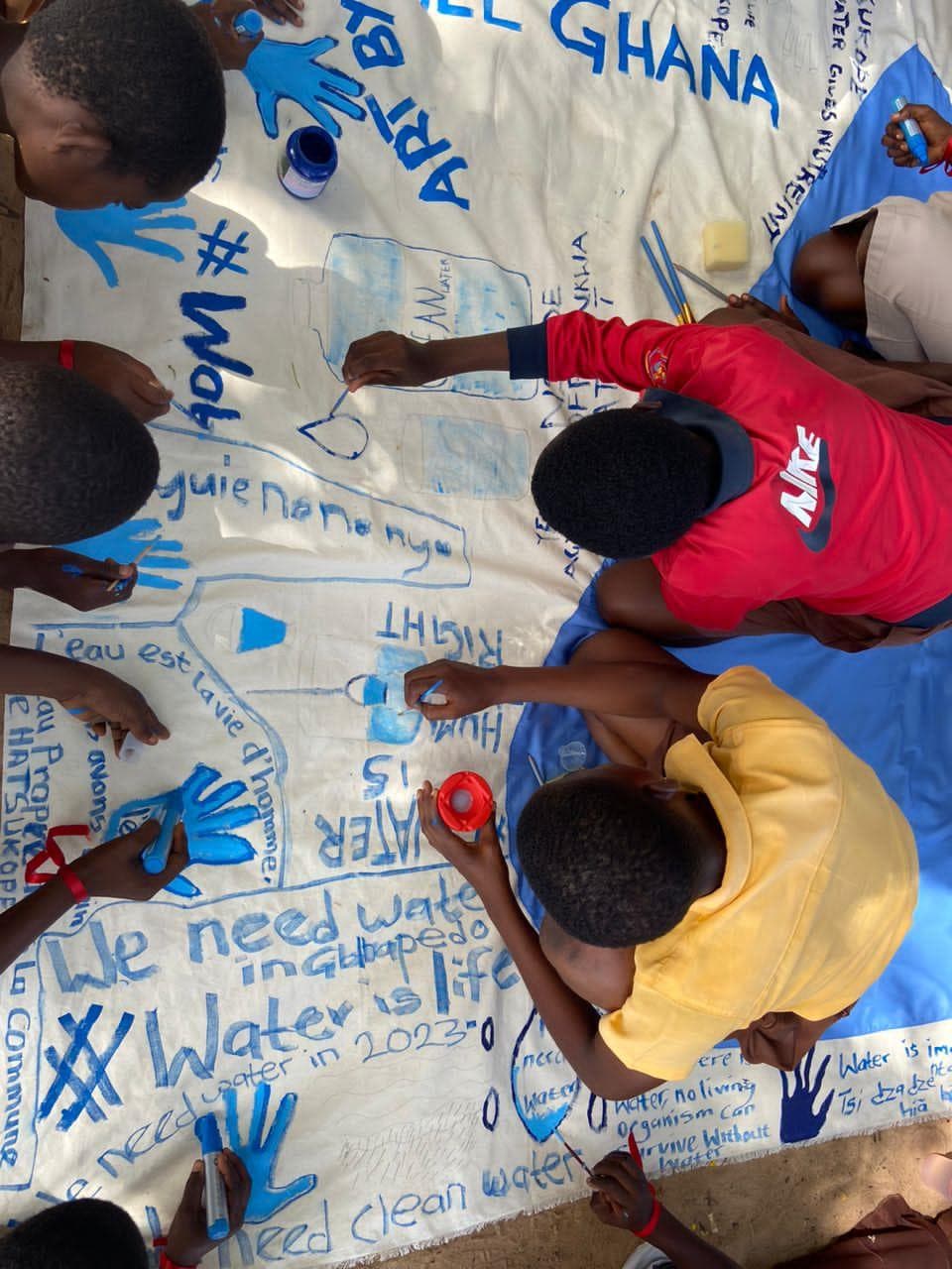 Des jeunes peignant une banderole communautaire pour la justice de l'eau lors d'une activation artistique au Ghana